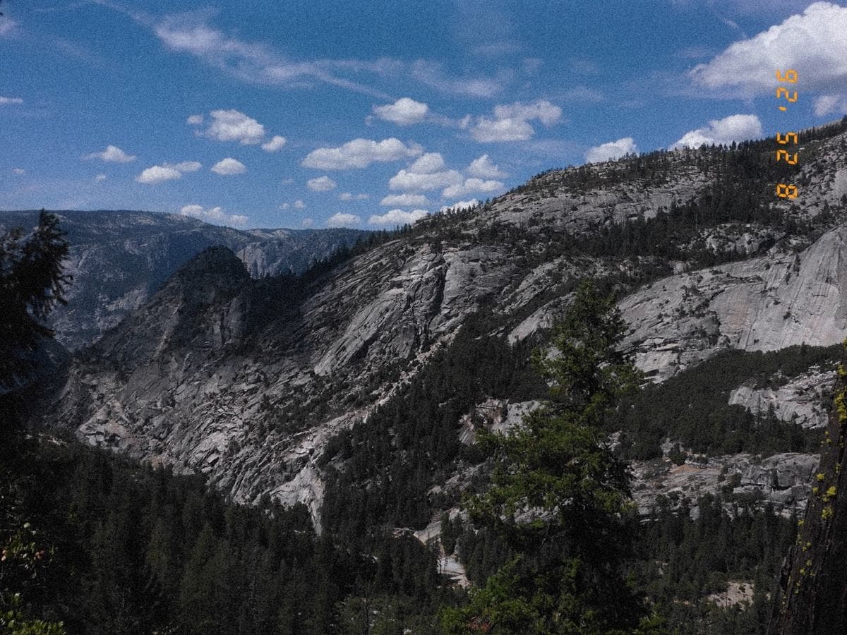 The valley from above: granite slopes falling into pine forest under a sky of scattered cloud.