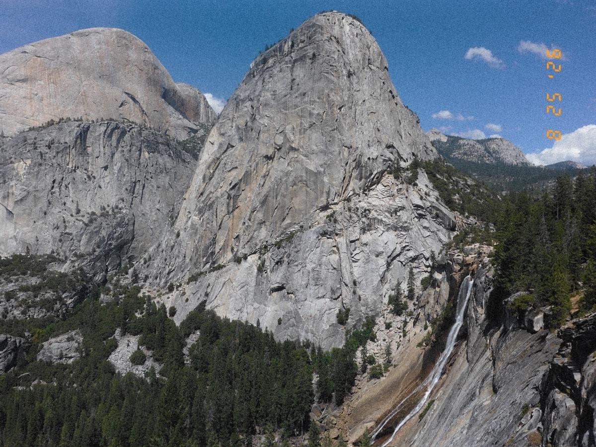Liberty Cap and Half Dome in full sun, with Nevada Fall dropping down the right of the frame.
